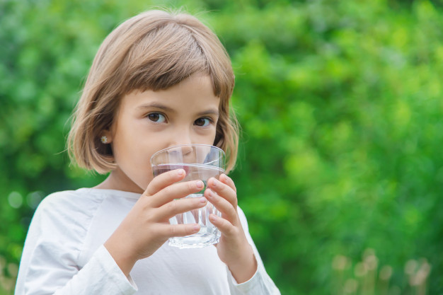Petite fille qui boie de l'eau dans un verre